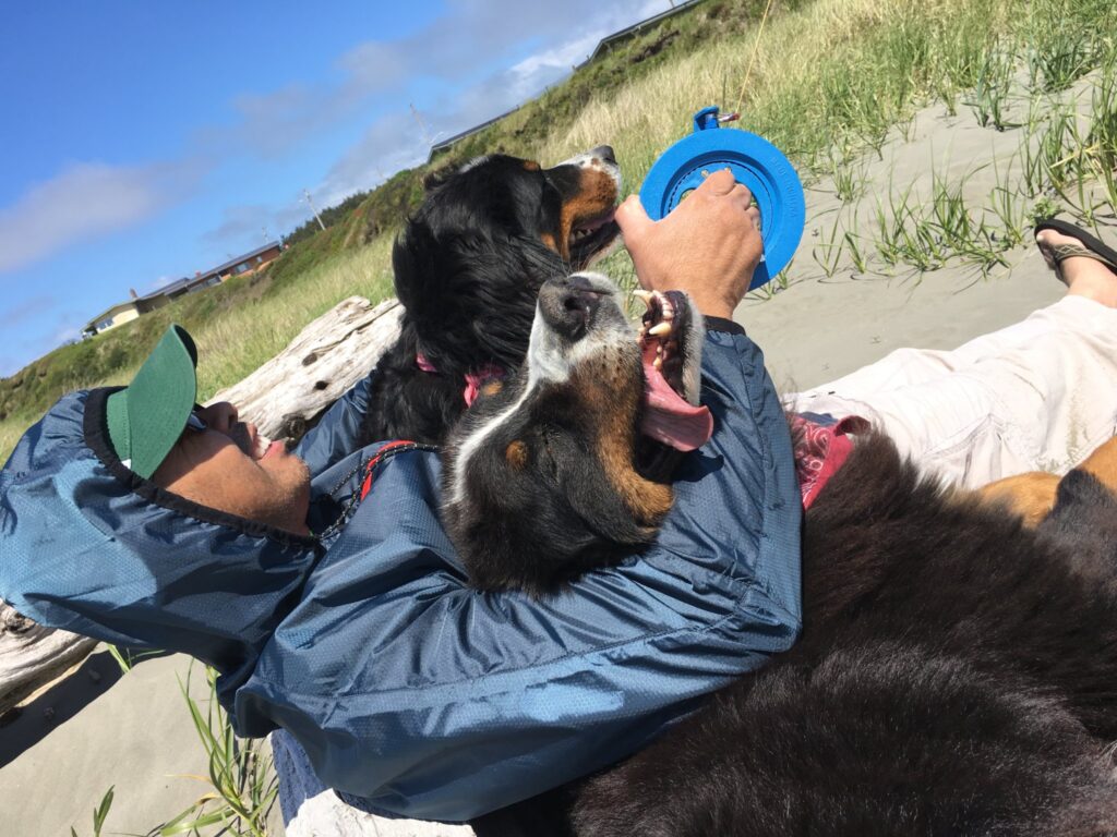 Allan sits with his two dogs on the beach