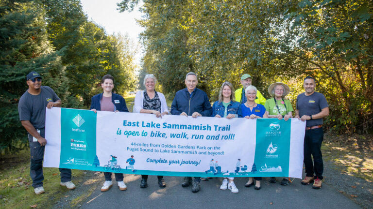 A group of people holding up a sign along a trail