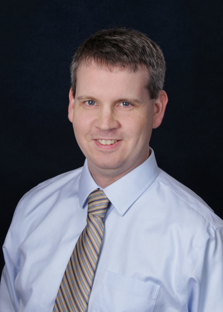 A headshot of a man wearing a shirt and tie