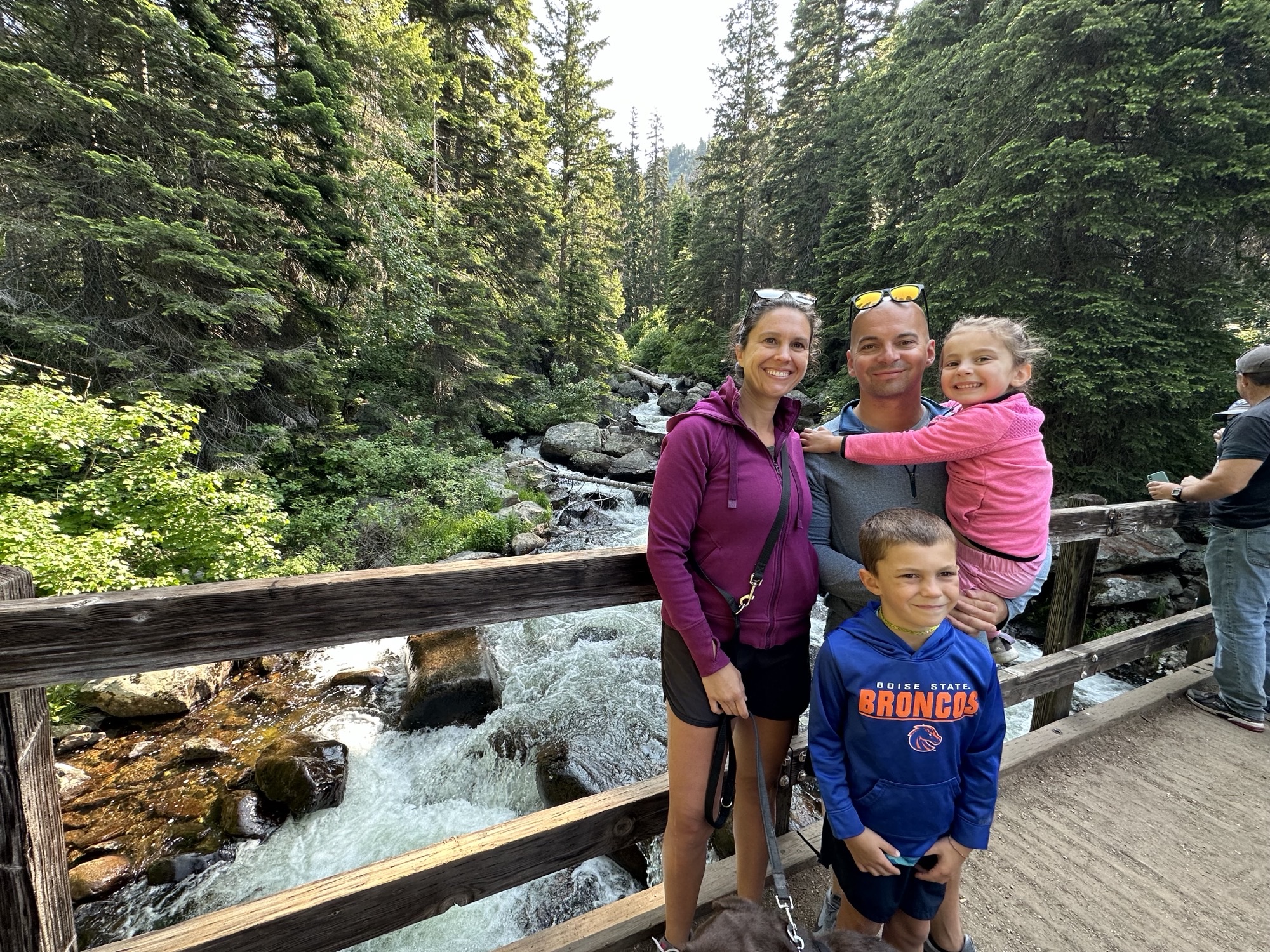 A man, woman, and two children stand on a bridge over a river