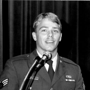A black and white photo of a man wearing a military uniform standing behind a pondium
