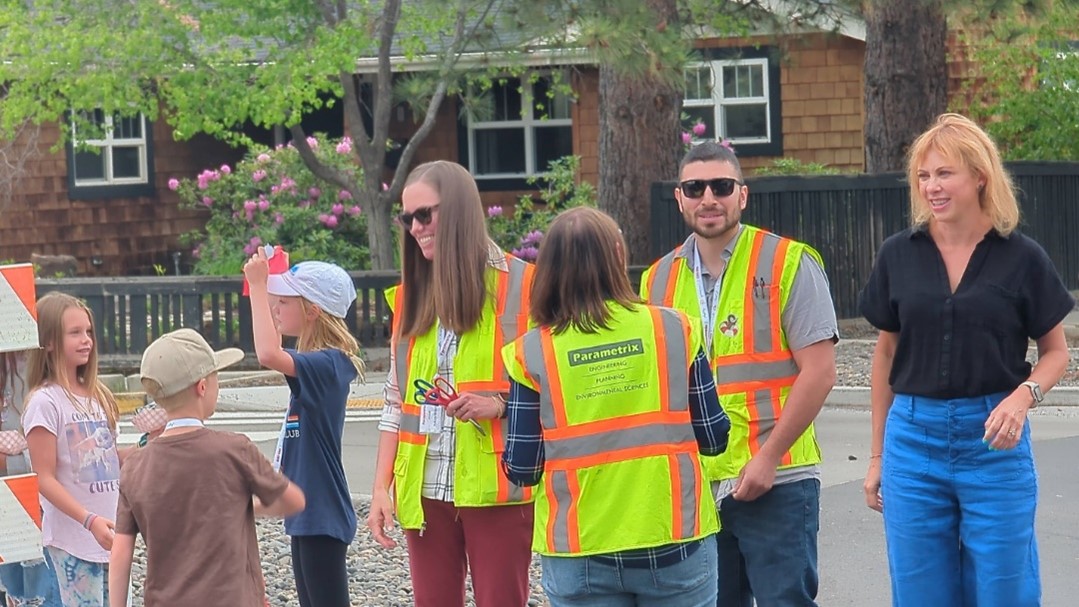 A group of people wearing safety vests mingle at the grand opening ceremony