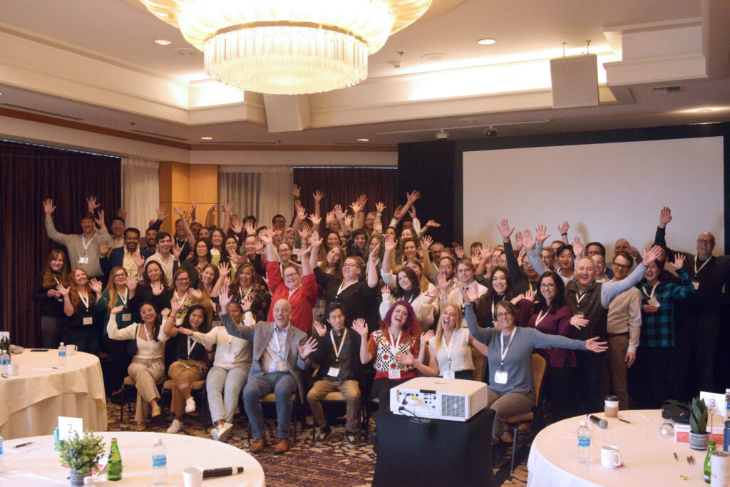 A group of people pose for a photo with their hands in the air.