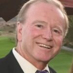 A man wearing a white collared shirt, jacket, and tie.