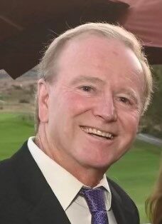 A man wearing a white collared shirt, jacket, and tie.