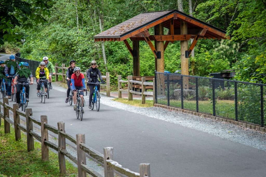 A group of people ride bikes along a paved trail