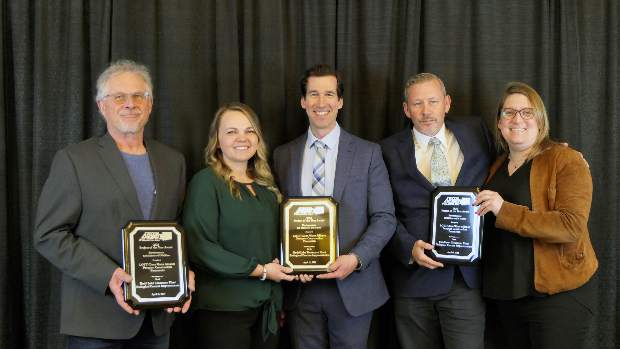 A group of five people pose for a photo holding an awards plaque