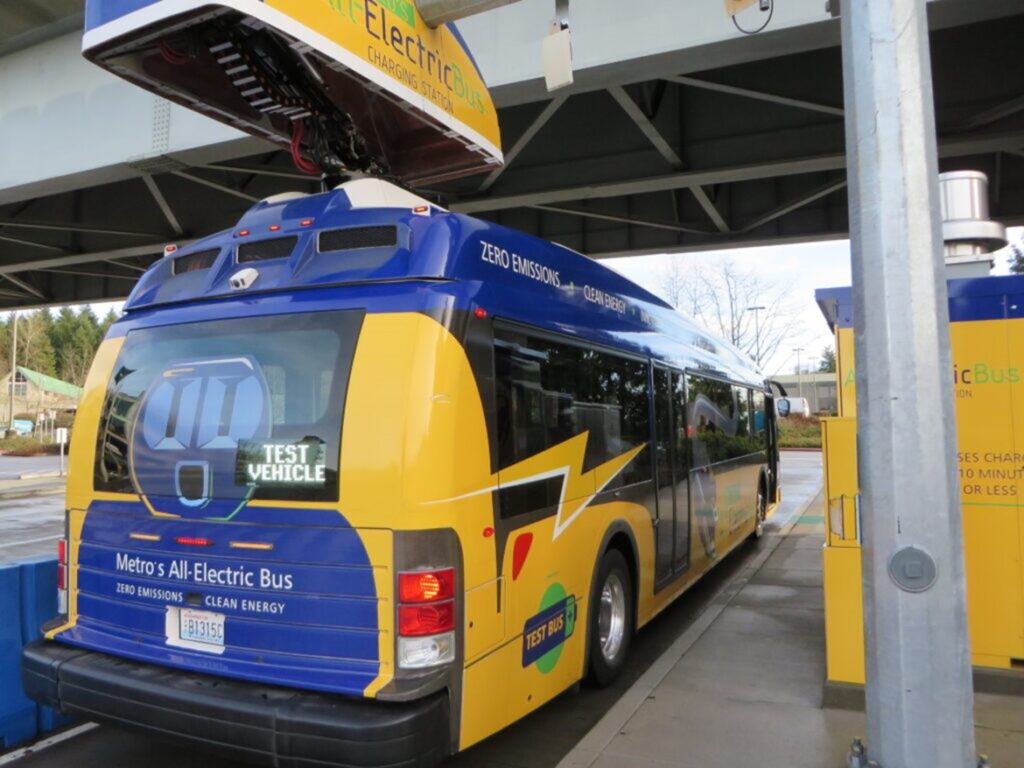 A blue and yellow electric bus in a charging station