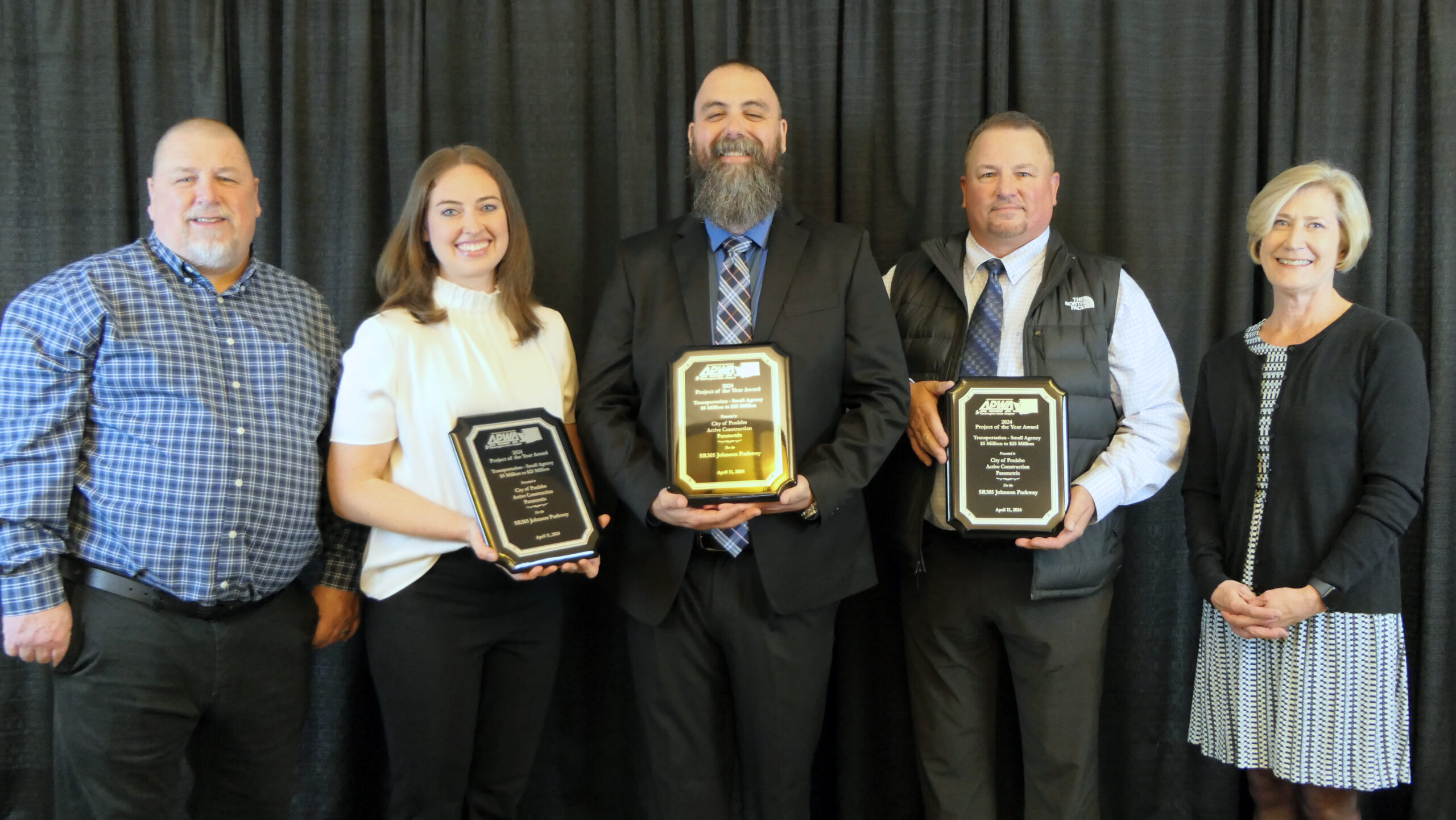 Five people pose for a photo holding award plaques.