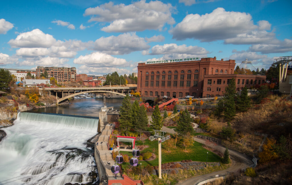 A bird's eye view of Spokane with a large brick building and bridge going over the river which flows down into the falls.