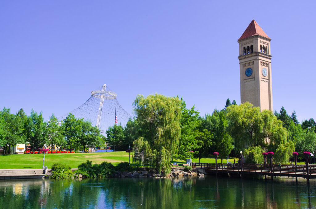 A park with a clocktower, bridge, and water