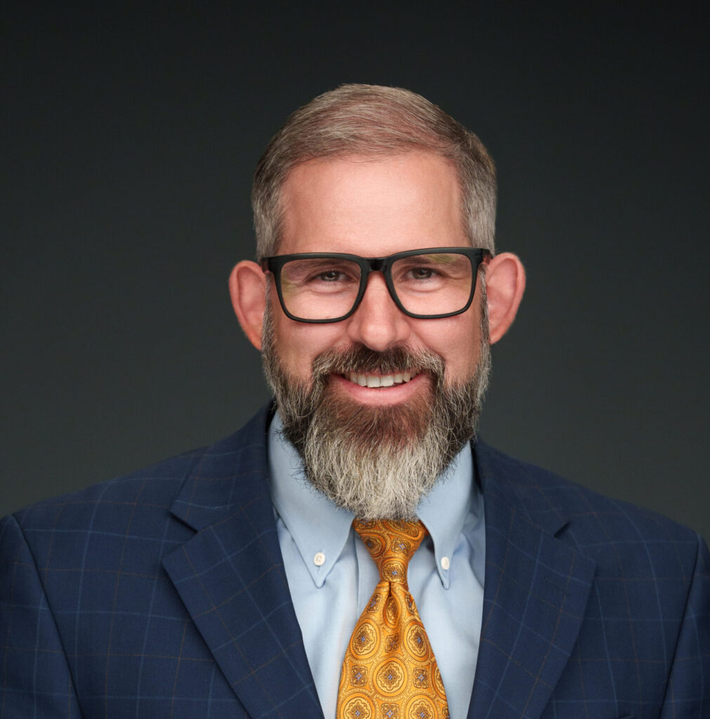 A man wearing a suite and tie and glasses.