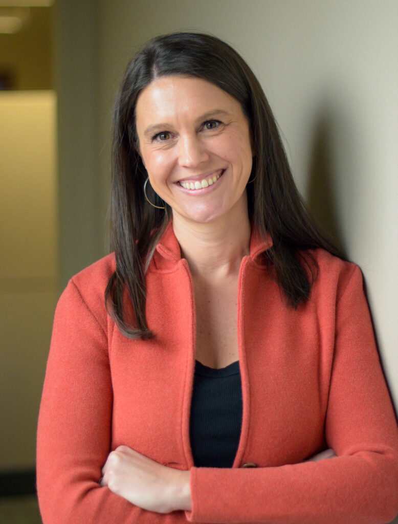 A woman smiling standing with her arms crossed