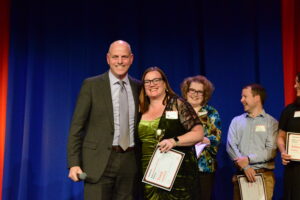 Two people on stage with one holding a certificate.