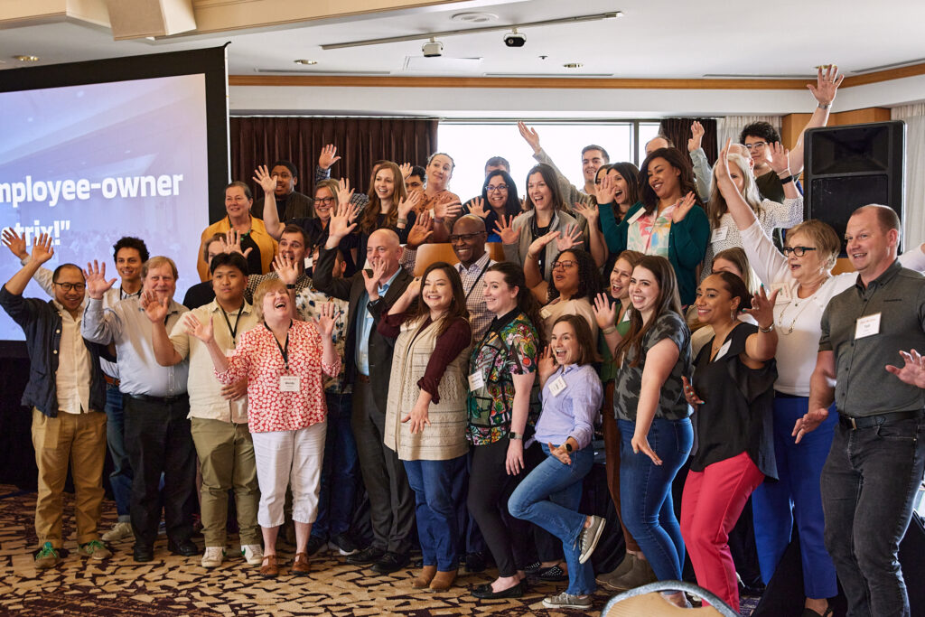 A group of employees raises their hands in excitement