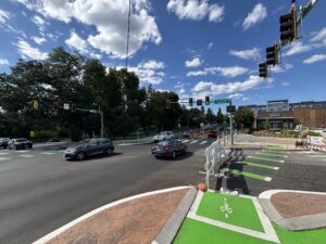 Cars drive by a green and white striped bike lane
