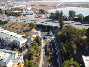 An aerial view of a roadway and overpass next to a body of water.