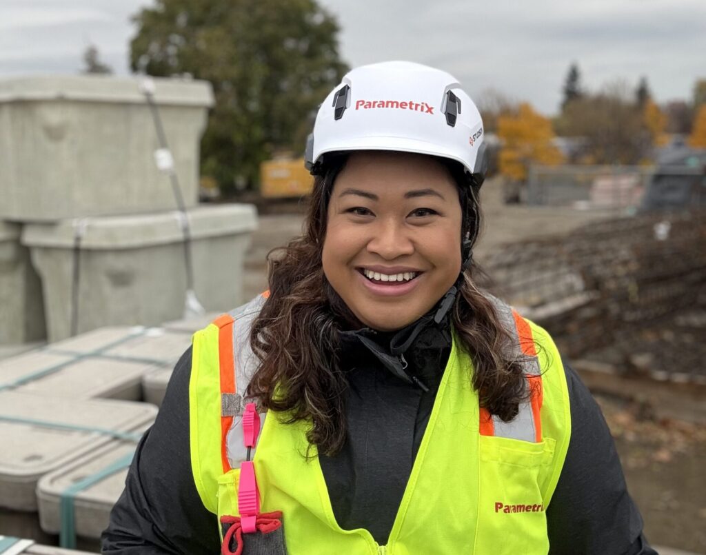 A person wearing a safety vest and hard hat in the field