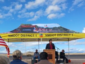 A person stands at a podium under a tent