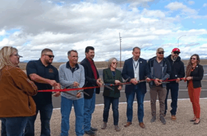 A group of people stand behind a ribbon with scissors