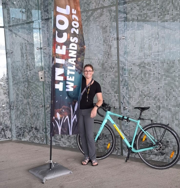 A person stands with a bike next to a sign