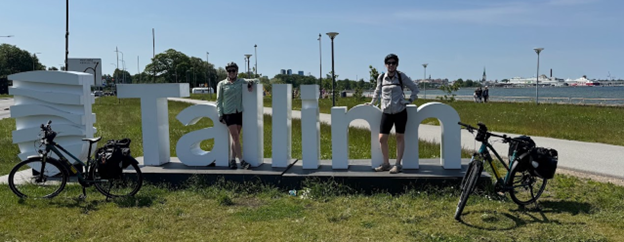 Two people pose with a large "Tallinn" sign