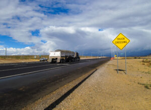 A truck crossing sign with a truck driving by