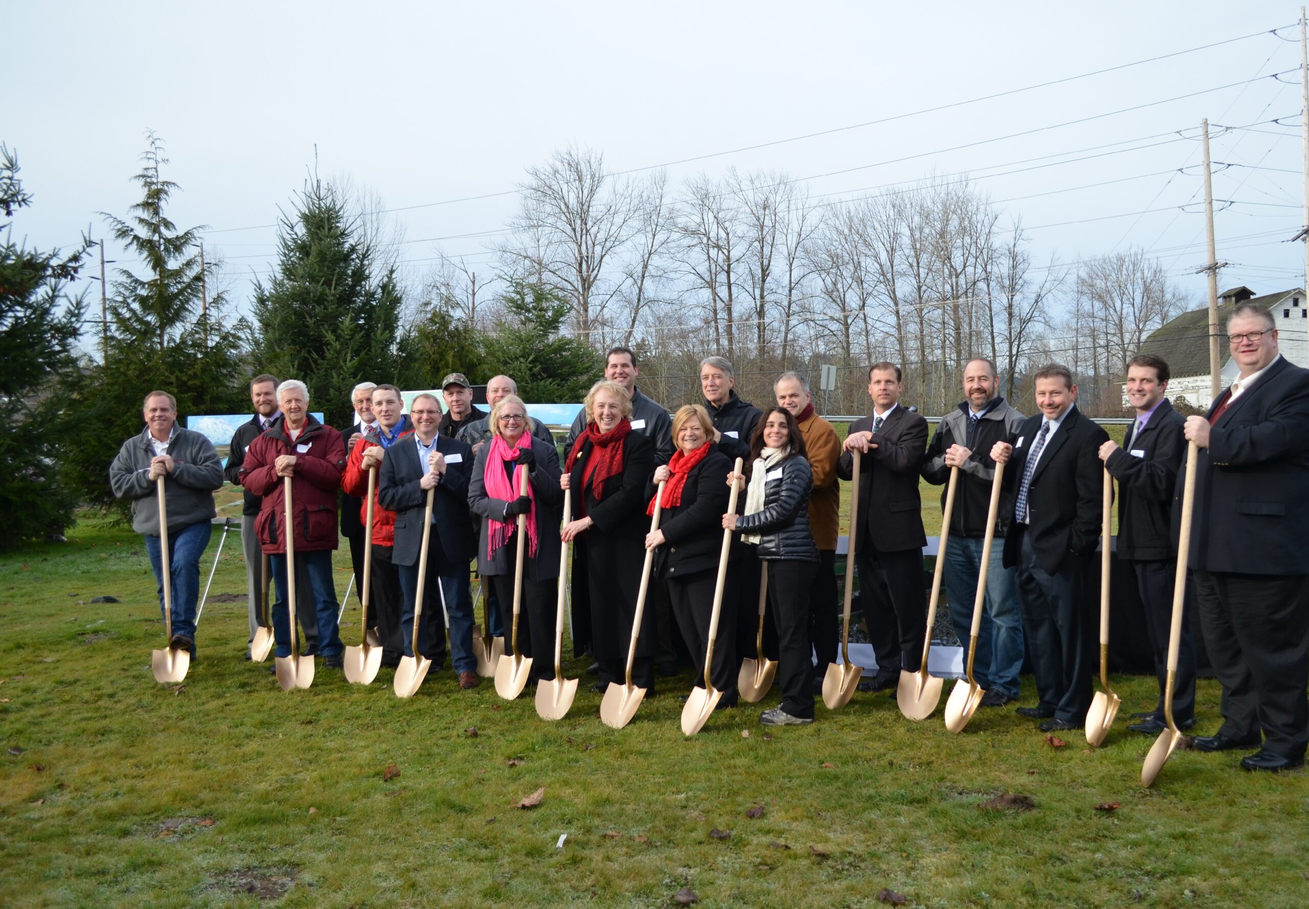 A group of people standing outside holding golden shovels