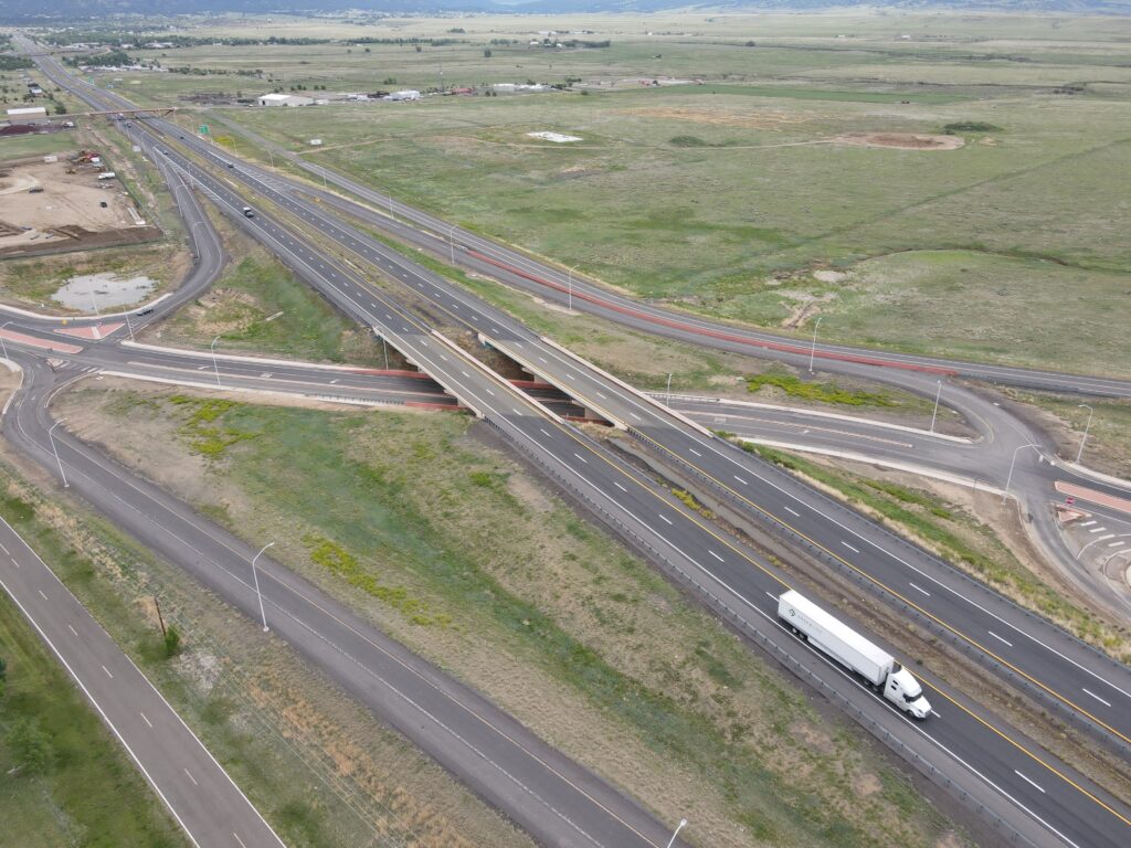 Aerial view of a complex highway interchange with multiple overpasses and curved ramps, trucks traveling on the roads.